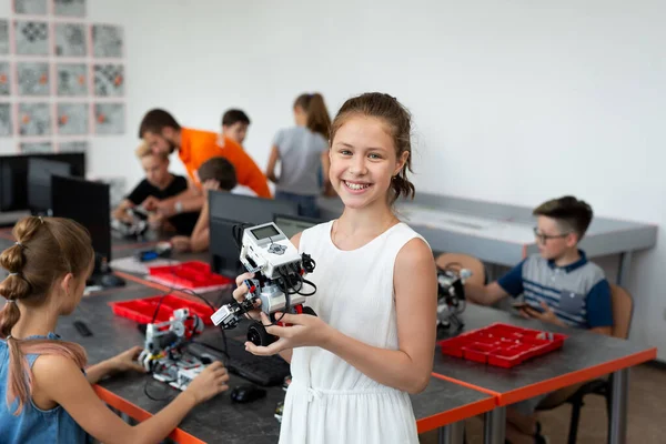 Portrait d'une écolière heureuse dans une classe de robotique, elle tient un robot assemblé à partir de pièces en plastique programmées sur un ordinateur. — Photo