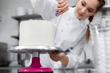 Pasta şefi pastayı kremayla katlıyor..