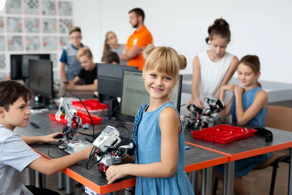 Portrait d'une écolière heureuse dans une classe de robotique, elle tient un robot assemblé à partir de pièces en plastique programmées sur un ordinateur. — Photo