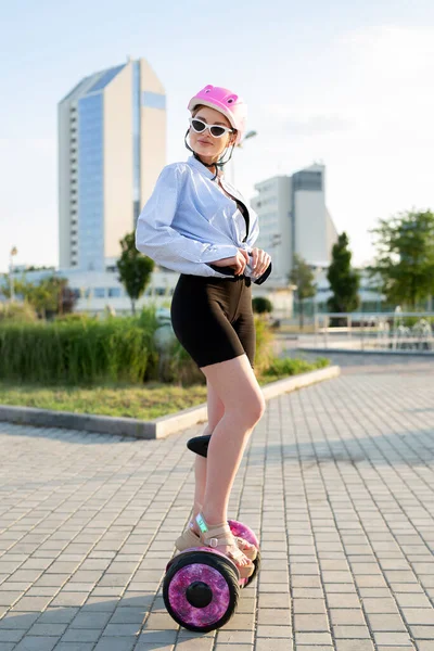 Ritratto di una bella donna su un hoverboard o su uno scooter giroscopico nel parco. — Foto Stock