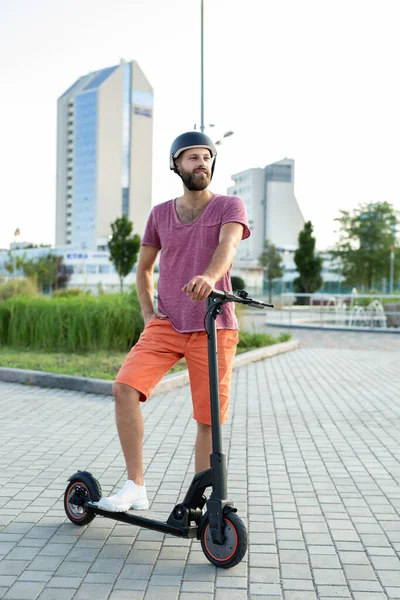 Hombre feliz monta un scooter eléctrico en el parque. — Foto de Stock