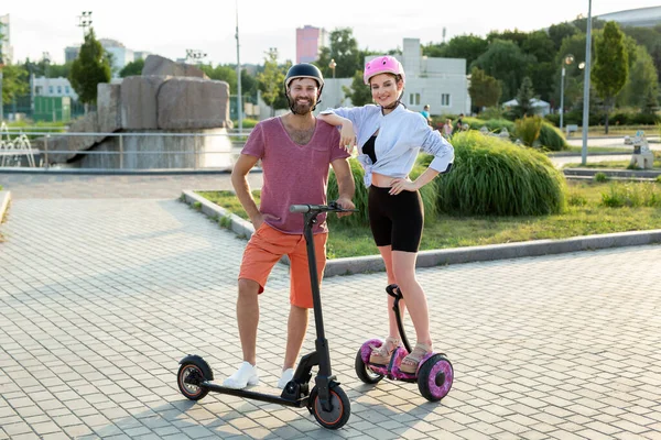 Felice uomo e donna in sella all'hoverboard e scooter nel Parco. — Foto Stock