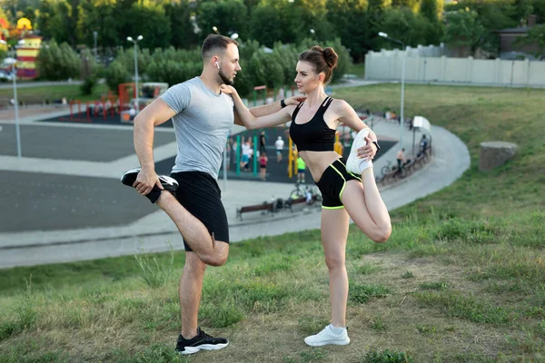 若いカップルは、日没時に夏の公園で屋外でトレーニング. — ストック写真