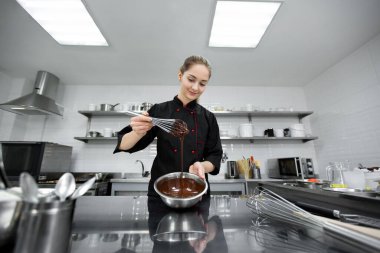 Pasta şefi çikolatalı ganache ile çırpıcıyı karıştırır.