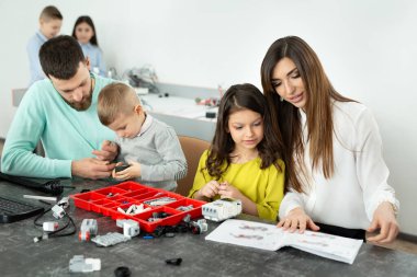 Robot kulübünde çocuklu bir aile bir robotu inşaatçıdan kontrol eder.