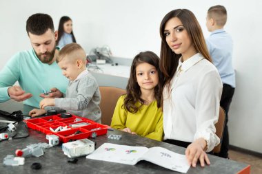 Robot kulübünde çocuklu bir aile bir robotu inşaatçıdan kontrol eder.