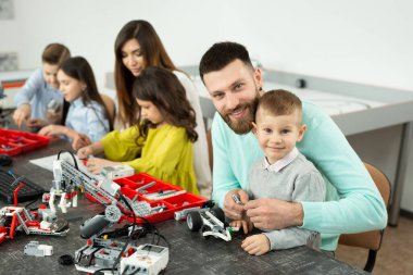 Robot kulübünde çocuklu bir aile bir robotu inşaatçıdan kontrol eder.