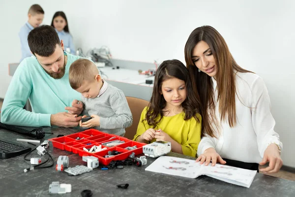 Familie mit Kindern in einem Robotikclub baut Roboter, die von einem Konstrukteur gesteuert werden — Stockfoto