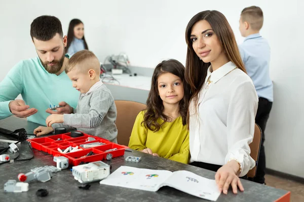 Familie mit Kindern in einem Robotikclub baut Roboter, die von einem Konstrukteur gesteuert werden — Stockfoto