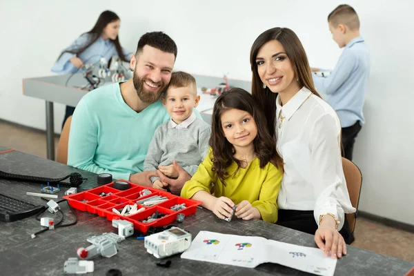 Gezin met kinderen in een robotclub maakt een robot bestuurd door een constructeur — Stockfoto