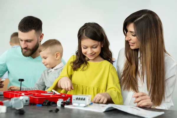 Familie mit Kindern in einem Robotikclub baut Roboter, die von einem Konstrukteur gesteuert werden — Stockfoto