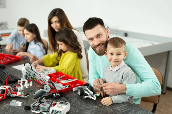 Gezin met kinderen in een robotclub maakt een robot bestuurd door een constructeur — Stockfoto