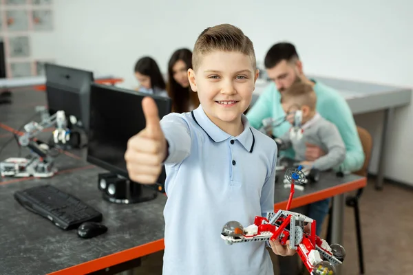 Portrait d'un garçon intelligent dans une classe de robotique à l'école, tenant un robot qu'il a assemblé à partir de pièces en plastique programmées sur un ordinateur — Photo