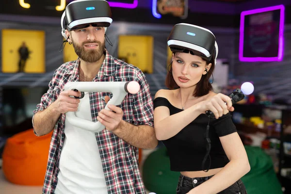 Retrato de un hombre y una mujer con un casco de realidad virtual con gafas y mandos en un club de juego — Foto de Stock