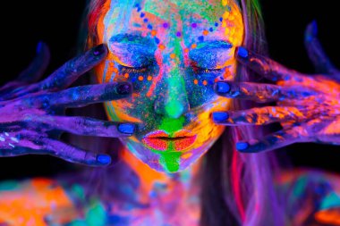 Neon ışıklı güzel bir genç kadın. Renkli makyajlı ve ultraviyole ışıkta poz veren floresan makyajlı bir modelin portresi.