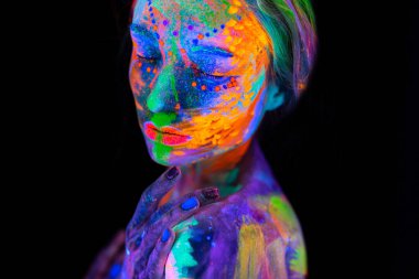 Neon ışıklı güzel bir genç kadın. Renkli makyajlı ve ultraviyole ışıkta poz veren floresan makyajlı bir modelin portresi.