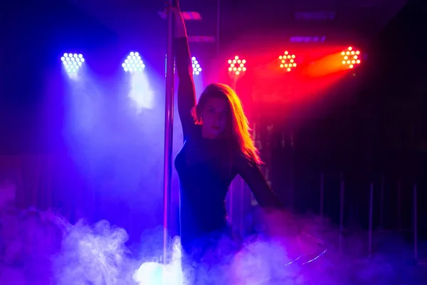 Direk dansı. Genç, narin, seksi bir kadın. Bir gece kulübünün içinde, ışık ve dumanla dans ediyor. — Stok fotoğraf