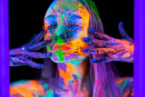 Hermosa joven en luz de neón. Retrato de un modelo con maquillaje fluorescente posando en luz UV con maquillaje colorido. — Foto de Stock