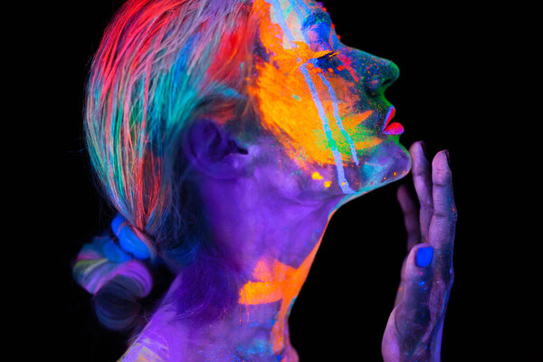 Красивая молодая женщина в неоновом свете. Портрет модели с флуоресцентным макияжем в ультрафиолетовом свете с красочным макияжем.