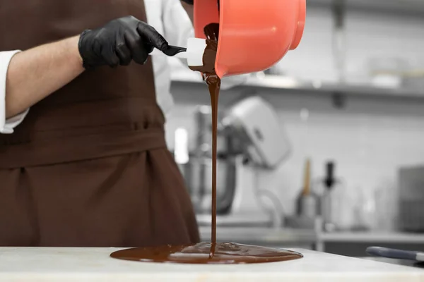 남성 초콜릿 용기에 녹인 초콜릿을 화강암 식탁에 붓다 — 스톡 사진