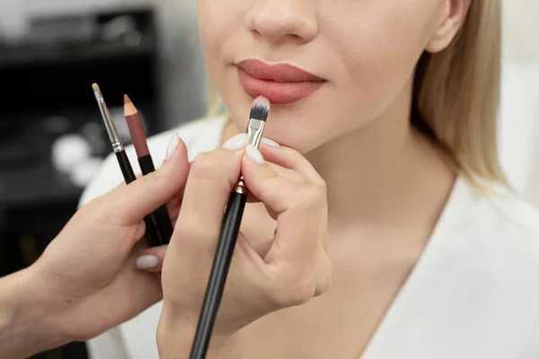 Cosmetóloga maquilladora pinta sus labios antes de un procedimiento de maquillaje permanente — Foto de Stock