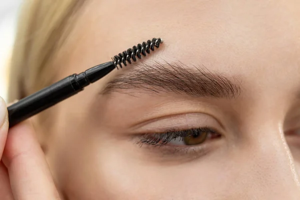 Primer plano hermosa mujer con herramienta de cepillo de cejas, maquillaje artista peines cejas de cerca — Foto de Stock