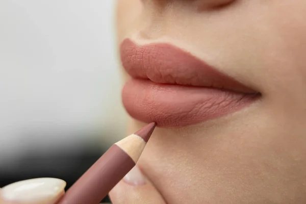 Szájfesték. Közelkép egy kozmetikusról, aki ceruzával festi az ajkait a végleges smink előtt.. — Stock Fotó