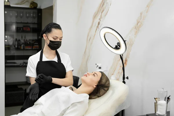 Косметолог надевает перчатки перед началом работы. Постоянный макияж губ — стоковое фото