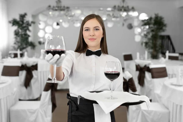 戴白色手套的女服务员拿着杯子和一瓶红酒 — 图库照片