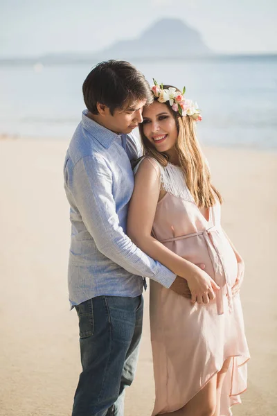 Mooi zwanger meisje en man op het strand. — Stockfoto