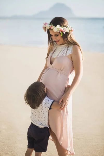 Um menino bonito beija sua barriga de mães grávidas na ilha — Fotografia de Stock