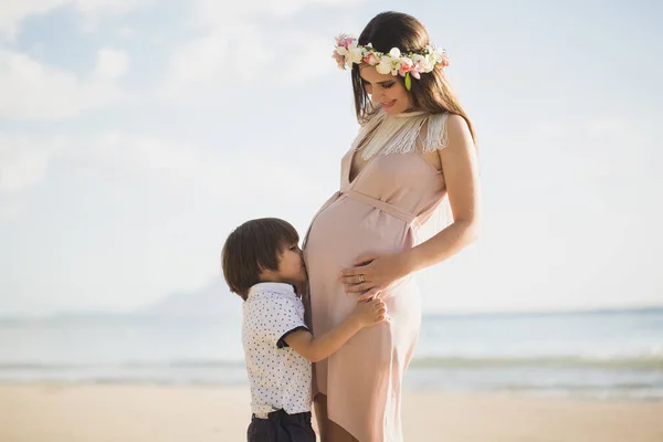 Een knappe jongen kust zijn zwangere moeders buik op het eiland — Stockfoto