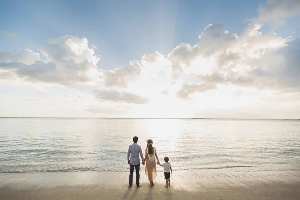 Вагітна мати батько і син на пляжі, в захваті від заходу сонця — стокове фото