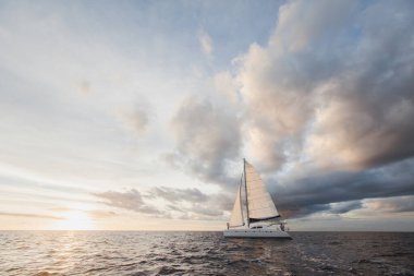 Yelkenli beyaz yat sıcak bir günde ada boyunca gider. Mavi deniz, mavi gökyüzü. Birbirlerine aşık genç bir çiftin gemisinde. Gelin ve damat. düğün teknesi gezisi.