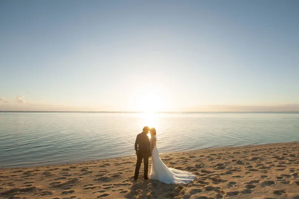 Наречений і наречений зустрічають захід сонця на пляжі . — стокове фото