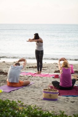 Kadınlar yoga egzersizleri yapıyor ya da Mauritius 'taki Hint okyanusunun boş bir sahilinde güvercin pozu veriyor..