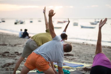 Kadınlar yoga egzersizleri yapıyor ya da Mauritius 'taki Hint okyanusunun boş bir sahilinde güvercin pozu veriyor..