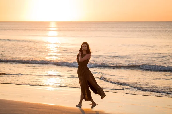 Gyönyörű nő naplemente háttérrel. Színes hajnal a tenger felett. Gondtalan nő élvezi a naplementét a parton. Boldog életmódot.. — Stock Fotó