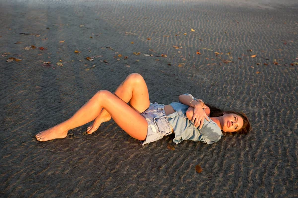 日落时，小女孩躺在沙滩上. — 图库照片