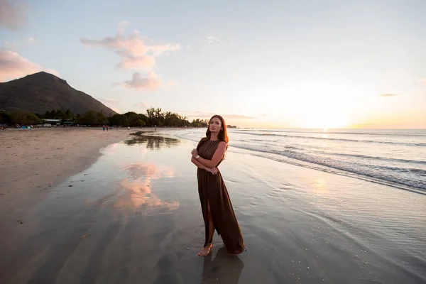 日没の背景に美しい女性。海の上にカラフルな夜明け。ビーチで夕日を楽しむ気の利いた女性。幸せな生活. — ストック写真