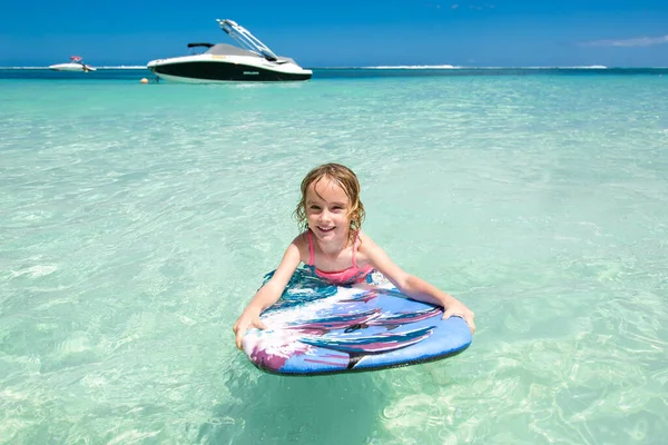 Kleines Mädchen - junge Surferin mit Bodyboard hat Spaß auf kleinen Meereswellen. Aktiver Lebensstil der Familie. — Stockfoto