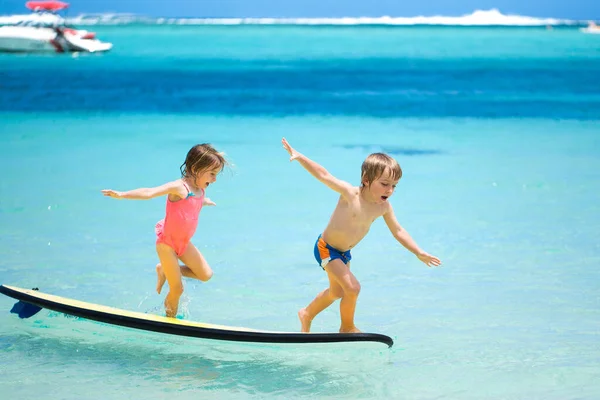 Zwillinge Bruder und Schwester haben Spaß beim Surfen im Meer. — Stockfoto