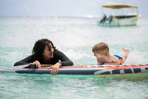 Máma a syn mají surfování v oceánu na tabuli. — Stock fotografie