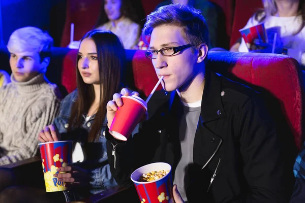 Jovem bebe de uma taça vermelha no cinema — Fotografia de Stock