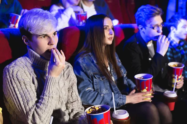 Jovem come pipocas no cinema e vê um filme — Fotografia de Stock