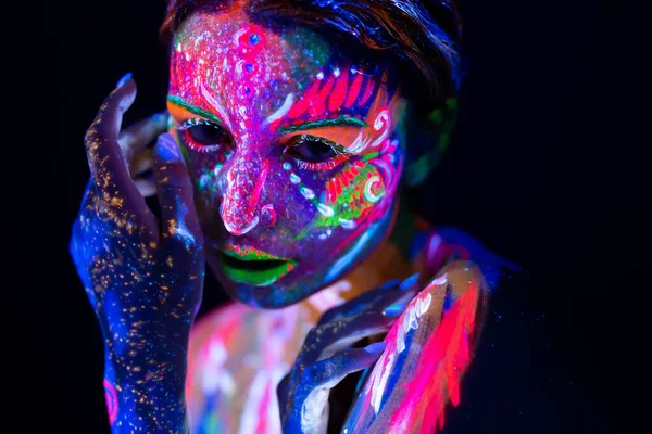 Mujer modelo de moda en luz de neón, retrato de hermosa modelo chica con maquillaje fluorescente, diseño Body Art de bailarina disco femenina posando en UV, cara pintada, maquillaje colorido, sobre fondo negro — Foto de Stock
