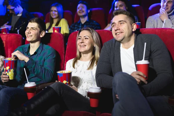 Przyjaciele siedzą i jedzą razem popcorn podczas oglądania filmów w kinie. Obraz Stockowy