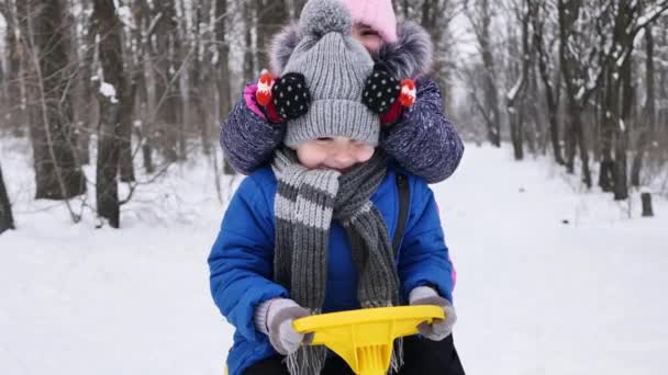 Vänner: en pojke och en flicka som leker i vinterskogen. Flickan sätter en hatt på pojkarnas ögon — Stockvideo
