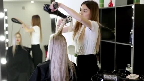 Drying long blonde hair with hair dryer and round brush. — Stock Video