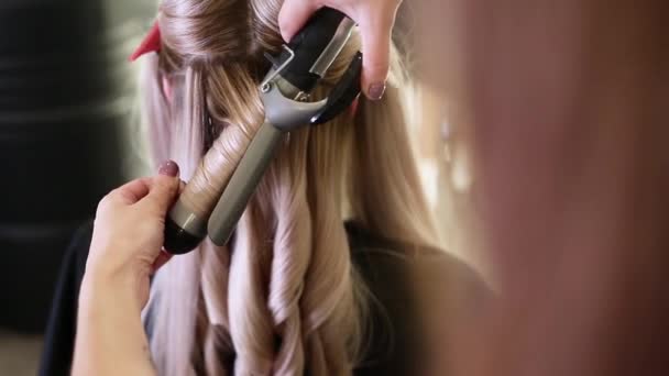 Close-up van stylisten hand met behulp van krultang werken voor vrouw client haar. — Stockvideo